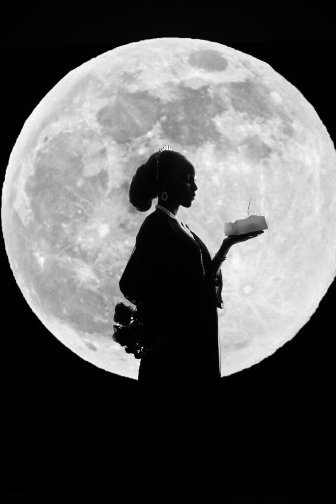 A candle held in front of a full moon for release ritual work.