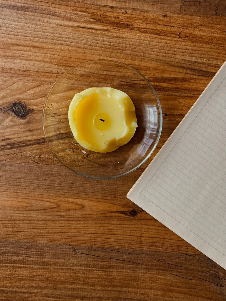Notebook and candle on a wooden table for starting a printable grimoire.