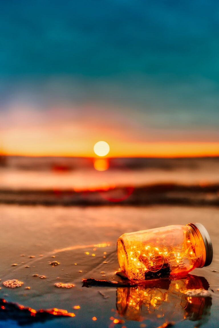 A glowing jar by water at sunset for moon water ritual ideas.