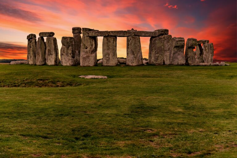 Stonehenge at sunset under a vivid orange sky for a summer solstice magic article