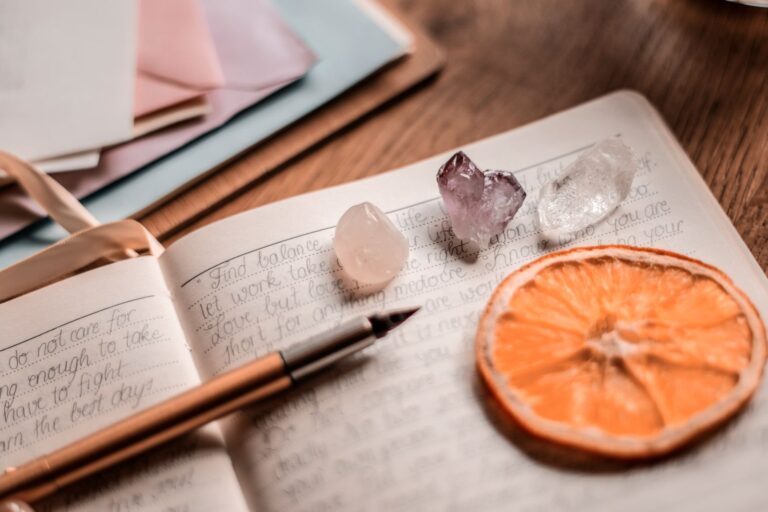 Notebook, pen, crystals, and dried orange for tarot journal ideas.
