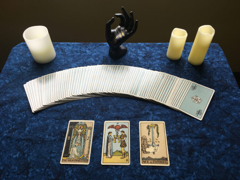 A three-card tarot spread with candles on a table.